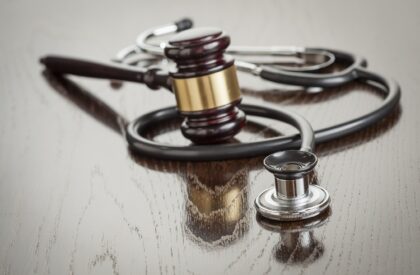 Gavel and Stethoscope on Reflective Wooden Table.