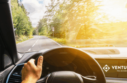 Person driving a car on a sunny summer day in Connecticut, practicing safe driving habits.