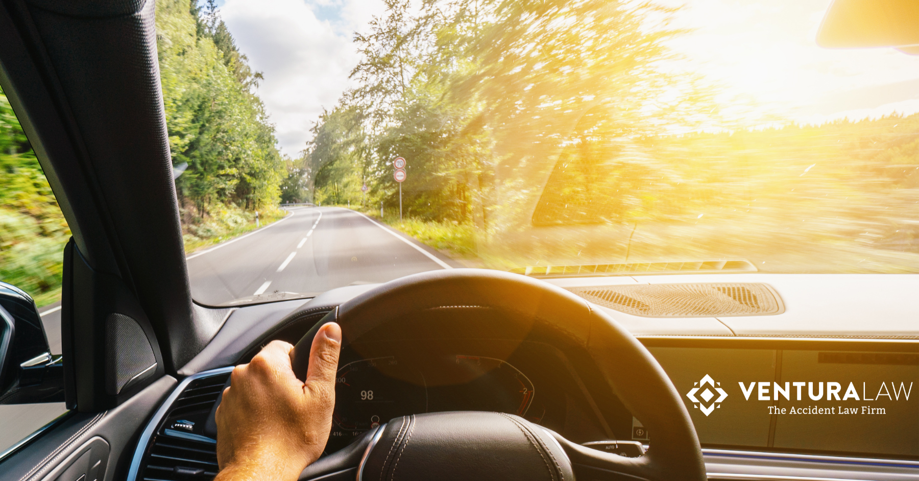 Person driving a car on a sunny summer day in Connecticut, practicing safe driving habits.